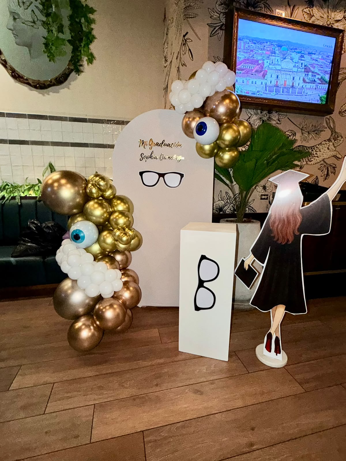Graduación de Oftalmología, arco dorado con ojos y anteojos
